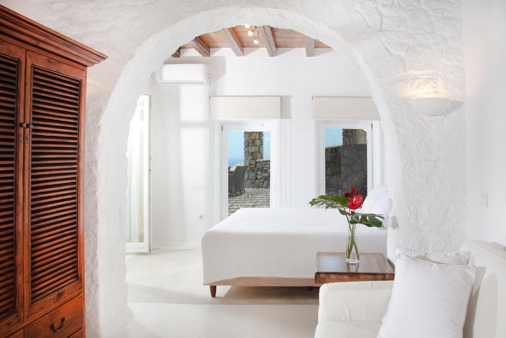 a bedroom with a white bed and a table at Aegean Stones in Agios Ioannis Mykonos