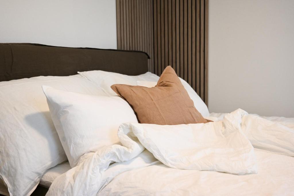 Una cama con sábanas blancas y almohadas. en Hotel feeling in the center of Trondheim, en Trondheim