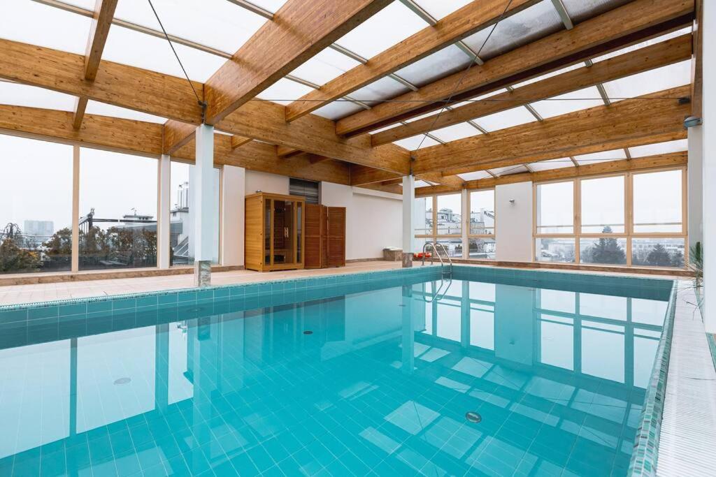 a large swimming pool with blue water in a building at Cozy, bright apartment. Swimming pool, parking, gym, PREMIUM in Warsaw