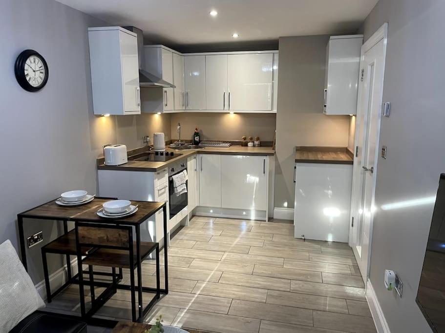 una cocina con armarios blancos y una mesa pequeña. en City Centre Seaview Apartment, en Brighton & Hove