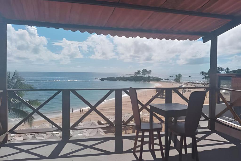 balcón con mesa y sillas y playa en Flats Nascer do Sol, en Cayru