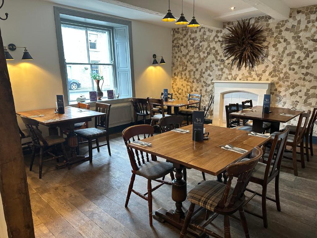 a restaurant with wooden tables and chairs and a fireplace at The White Bull in Gisburn