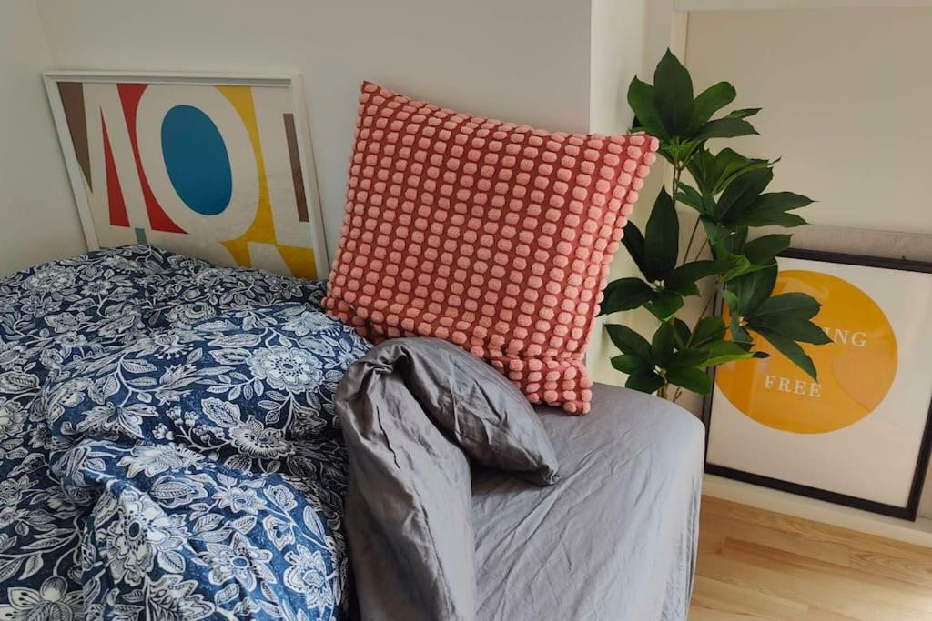 una cama con almohadas naranjas y una planta al lado en Lille nest en Rødovre