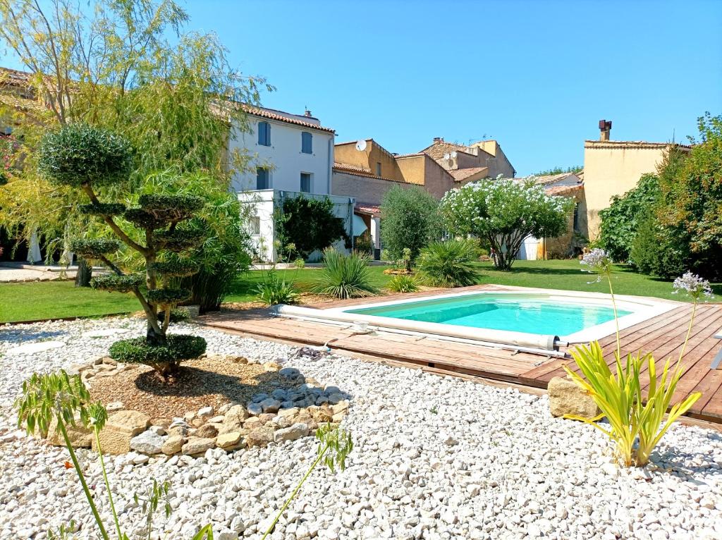 una piscina en un jardín con un árbol y rocas en Chez Sonia, en Sarrians