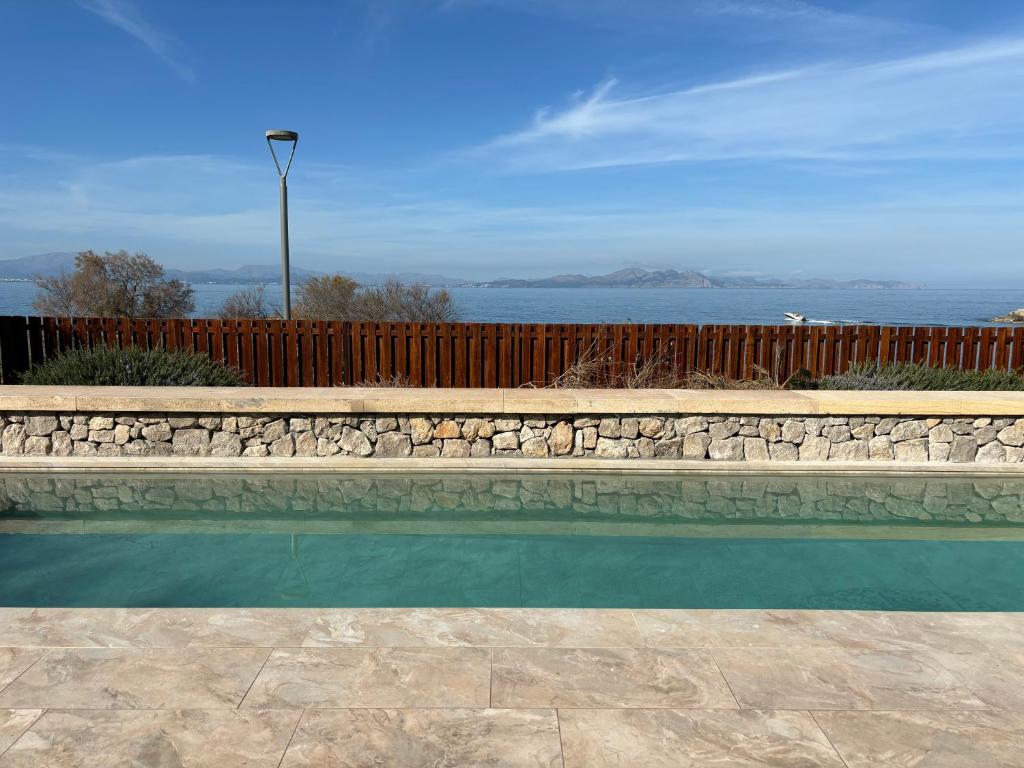 une piscine avec un mur en pierre et une clôture dans l'établissement Villa Catalá, à Colònia de Sant Pere