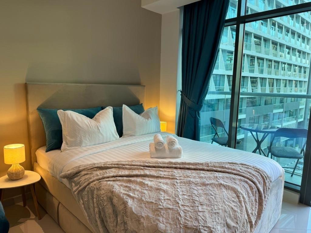 a bedroom with a large bed with two towels on it at Beachside Bliss: Stylish New Studio at Seven Palm in Dubai