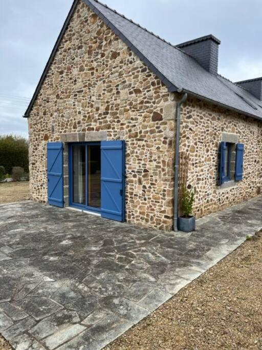 un bâtiment en briques avec des portes bleues et une usine de pot dans l'établissement Ti Mamm Gozh, à Plouha