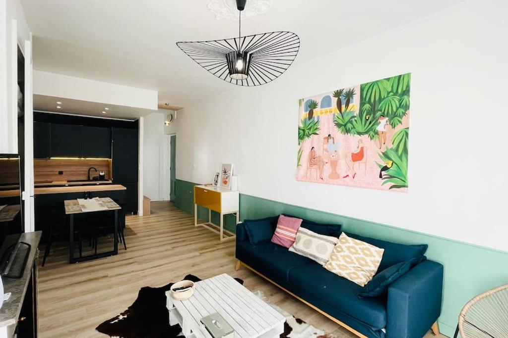 Il comprend un salon avec un canapé bleu et une cuisine. dans l'établissement Appartement rénové proche du parc de la tête d'or, à Villeurbanne