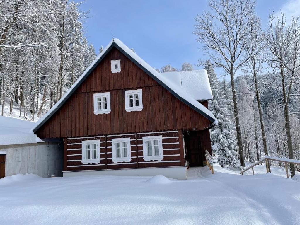 una pequeña casa de madera con nieve en el suelo en Chaloupka, en Rokytnice nad Jizerou