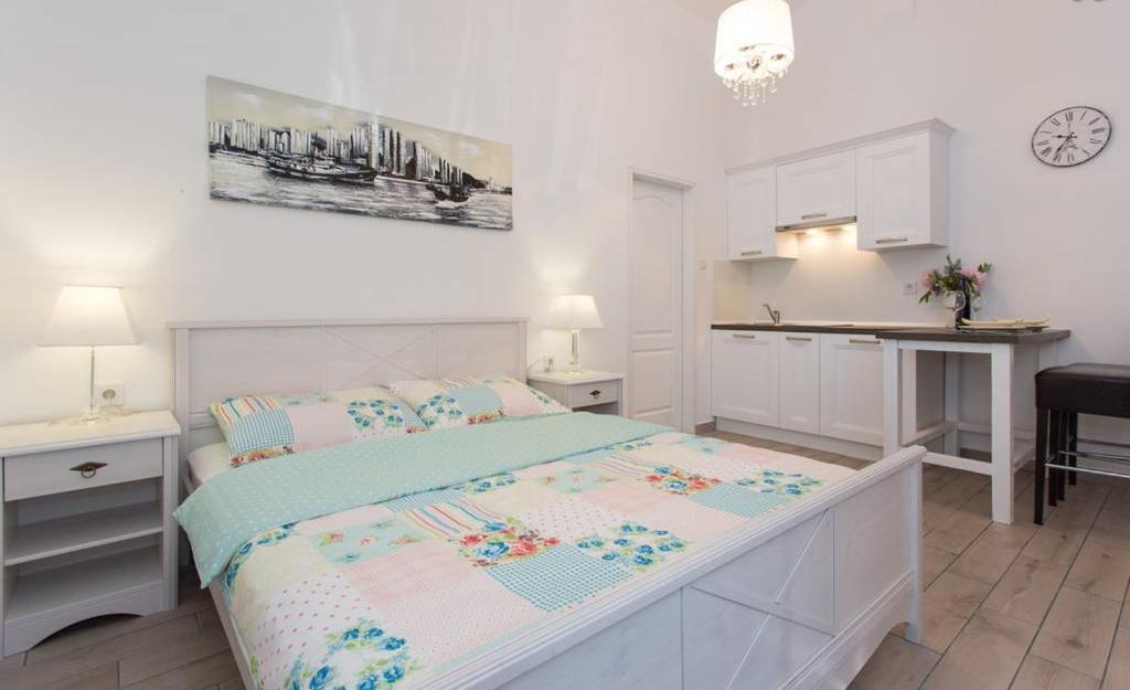 a white bedroom with a bed and a kitchen at Studio stonehouse in Ičići