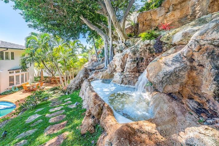 a waterfall on a rocky hill with a house at Villa Ahina in Honolulu
