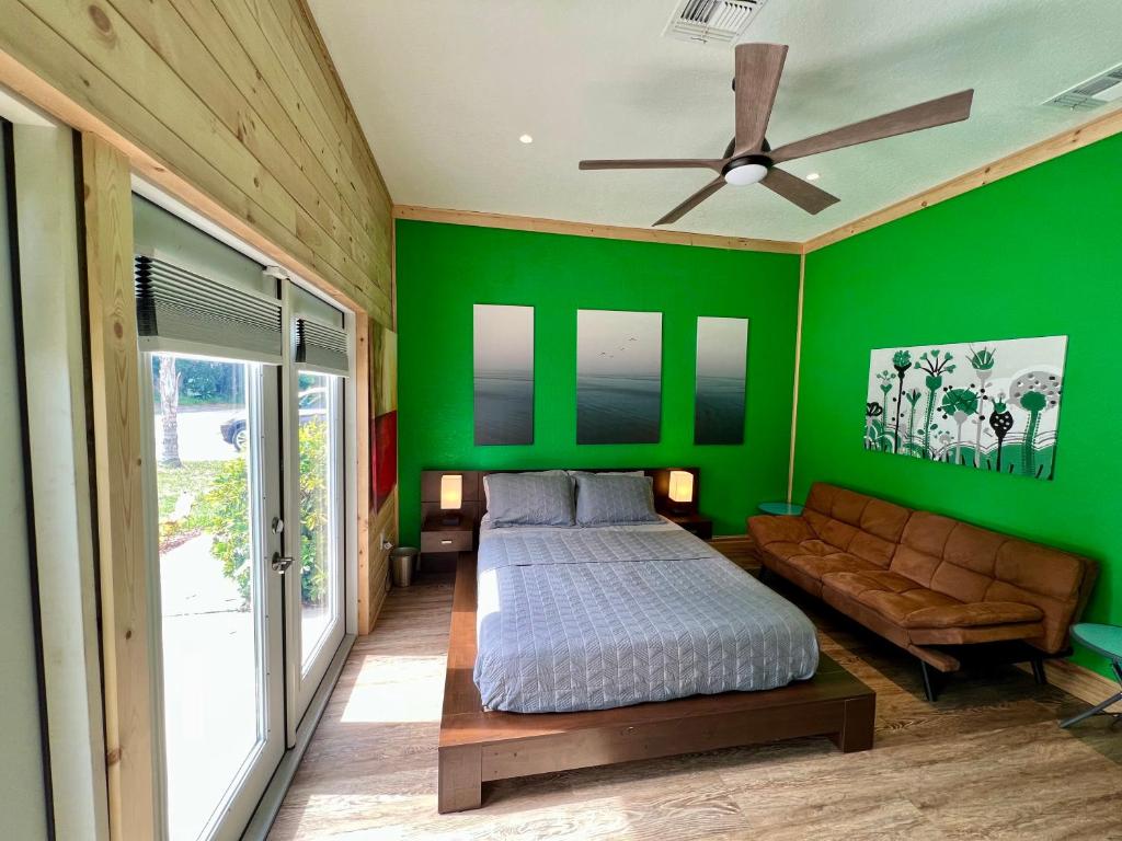 een groene slaapkamer met een bed en een bank bij The Tatman Evergreen Suite in Lake Alfred
