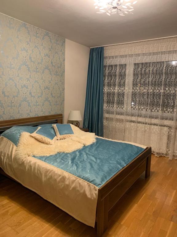 um quarto com uma cama com um edredão azul e uma janela em Leon’s Apartment em Krefeld