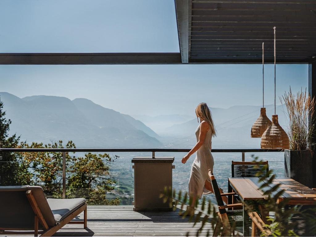 une femme marchant sur une terrasse donnant sur l'océan dans l'établissement farnhaus, à Tirolo