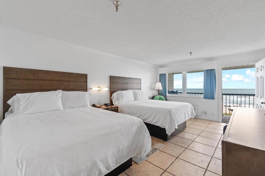 a hotel room with two beds and a balcony at Ocean Isle Inn in Ocean Isle Beach