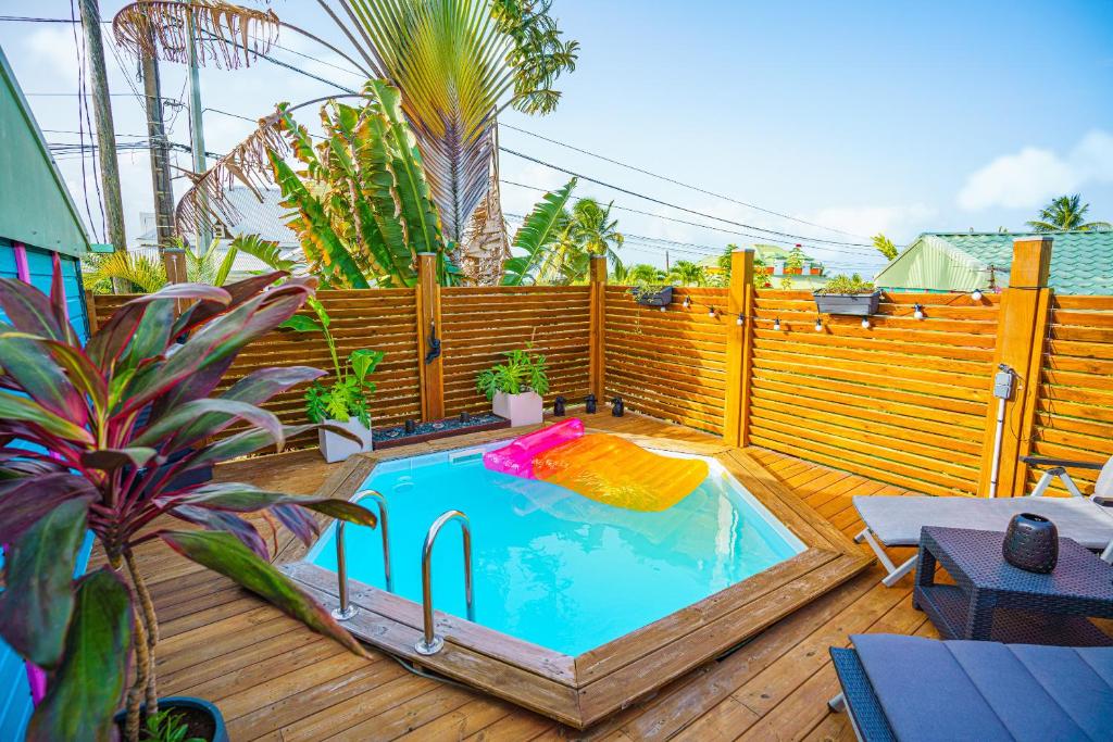 a swimming pool on a deck with a wooden fence at Au cœur du papillon piscine privée in Goyave