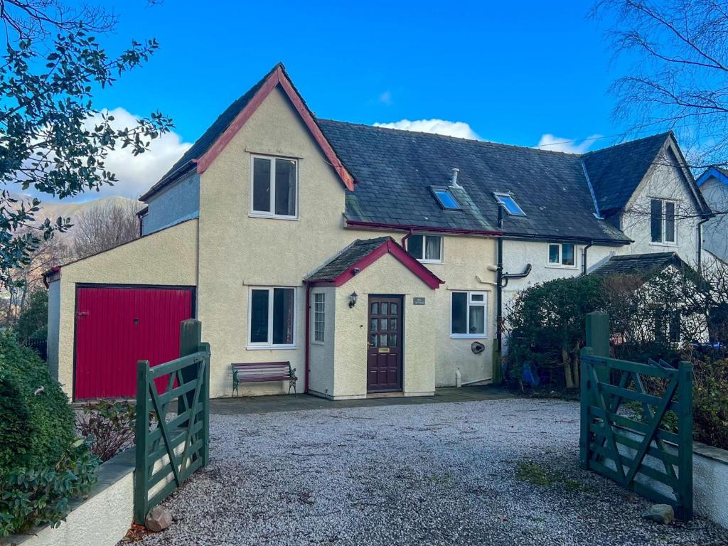 una casa grande con garaje rojo y puerta en Hill Cottage, Braithwaite en Braithwaite
