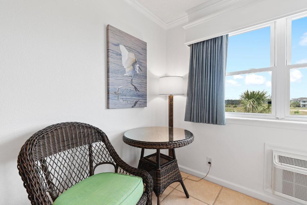 a room with a chair and a table and a window at Ocean Isle Inn in Ocean Isle Beach