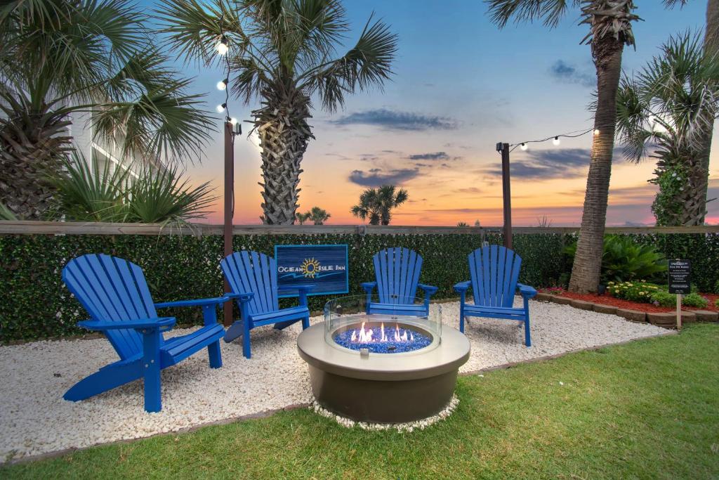 four blue chairs and a fire pit in a yard at Ocean Isle Inn in Ocean Isle Beach