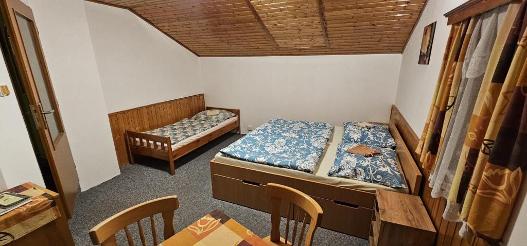 two beds in a room with a table and chairs at Pension u Havrana in Jetřichovice