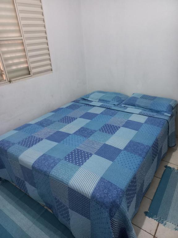 a blue and white bed in a room with a window at Quarto privativo em casa de condomínio in Cuiabá