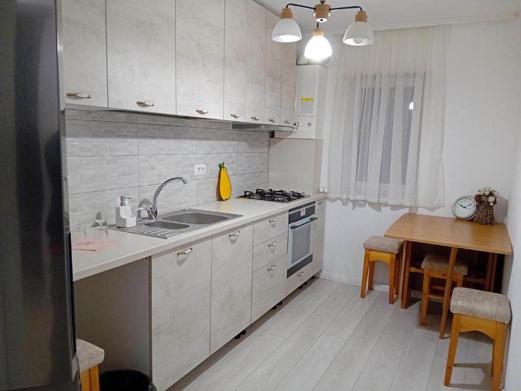 a white kitchen with a sink and a table at Apartment Rezidence in Suceava