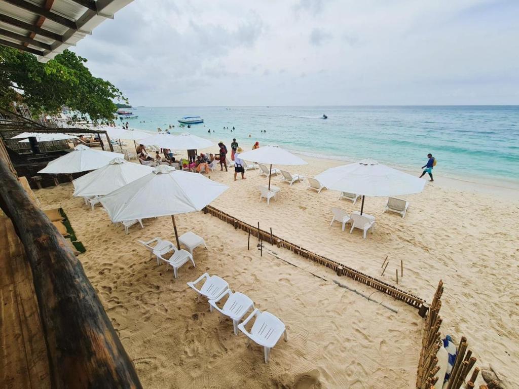 a beach with white umbrellas and chairs and the ocean at ROCHA BEACH CLUB in Barú