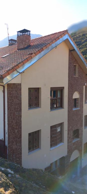 un edificio con ventanas y techo de baldosa en La Cuestina, en Llánaves de la Reina