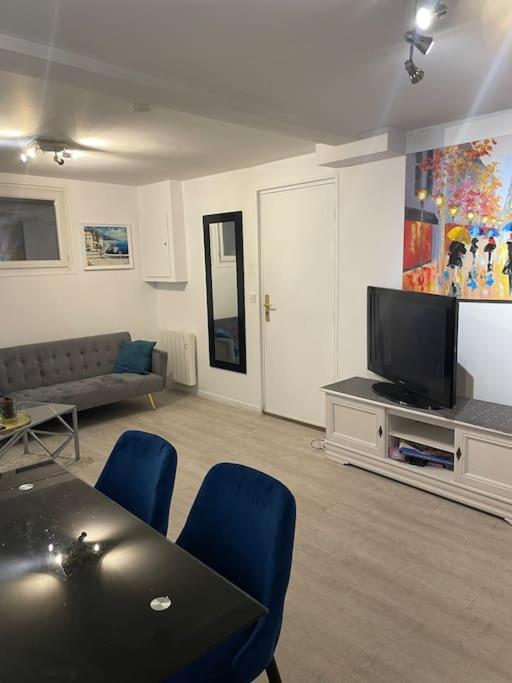 un salon avec une télévision, une table et des chaises dans l'établissement Porte de Paris- les Puces, à Saint-Ouen