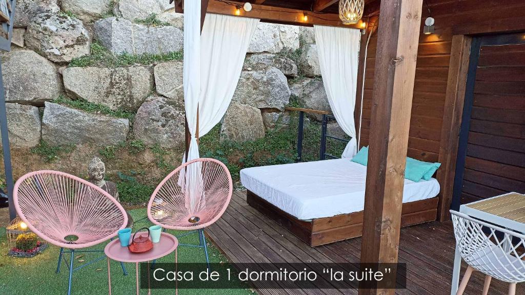 eine Veranda mit einem Bett und zwei Stühlen auf einer Terrasse in der Unterkunft NidoGredos Cabañas Ecológicas de Diseño in El Tiemblo