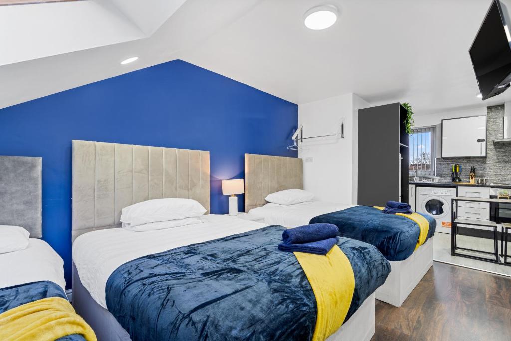 2 camas en un dormitorio con una pared azul en Cosy Apartments - City Living Made Elegant -, en Birmingham