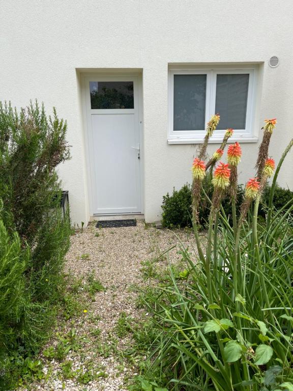 a white door of a house with flowers in front at Beau studio équipé - Calme et confortable in Bourg-en-Bresse