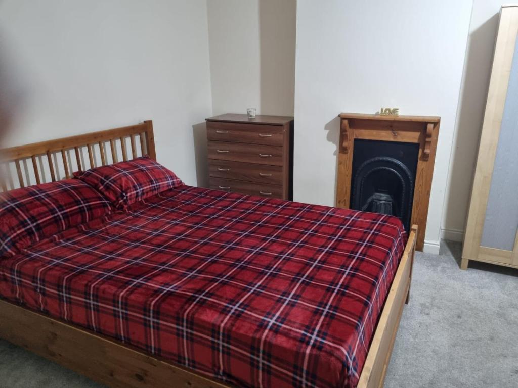 um quarto com uma cama, uma cómoda e uma lareira em Home away from home em Leicester