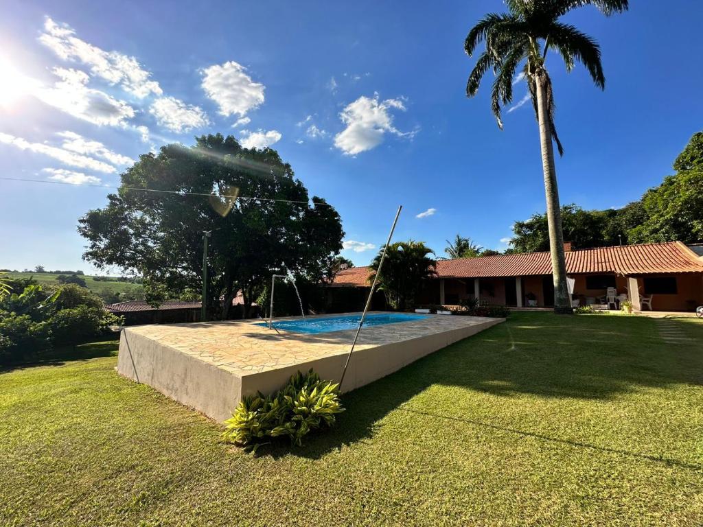 um quintal com uma piscina e uma palmeira em Chácara Marretto, ambiente acolhedor e familiar dentro da cidade de Tatuí. em Tatuí