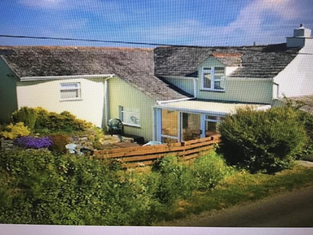 une maison avec une clôture en bois devant elle dans l'établissement Holiday Cottage Cornwall, à Delabole