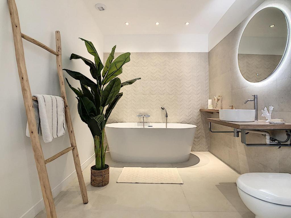 La salle de bains est pourvue d'une baignoire blanche et d'une plante. dans l'établissement - - - Maison ŪMA - - - Wifi, Mer et Centre, à Marseille
