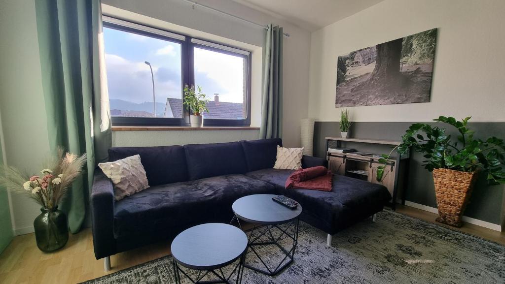sala de estar con sofá azul y 2 mesas en Ferienwohnung Talblick, en Bad Lauterberg