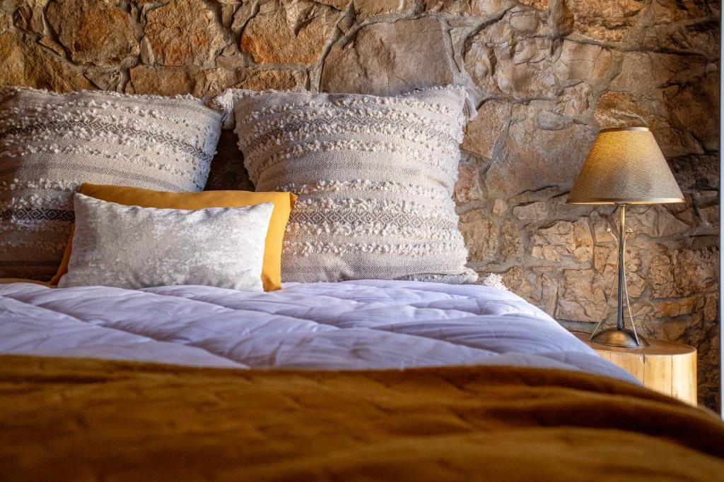 Un dormitorio con una cama azul con almohadas y una pared de piedra. en O Refúgio das Buracas, en Condeixa a Nova