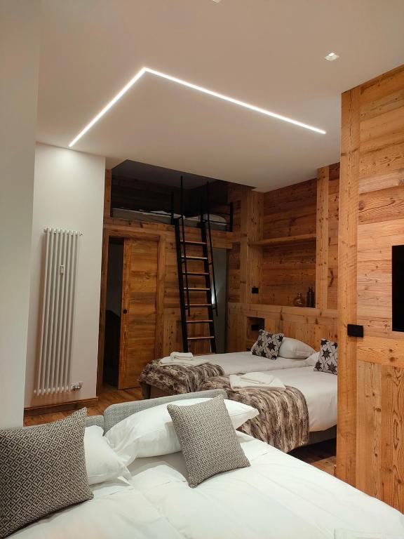 two beds in a room with wooden walls at Fior di Roccia Apartments- in centro Cervinia, sauna privata, Matterhorn dream in Breuil-Cervinia