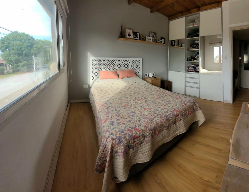 1 dormitorio con cama y ventana grande en Casa del parque en Necochea