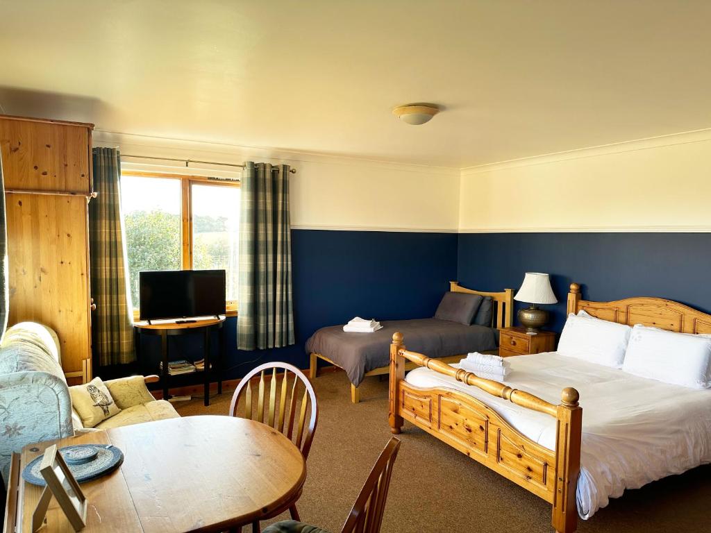 Habitación de hotel con 2 camas y sala de estar. en Orchard House Lodges by Ecohuman en Haddington