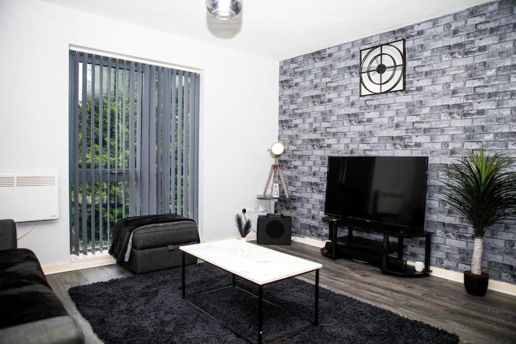 a living room with a tv and a brick wall at Stylish two-bedroom Salford Quays apartment in Manchester