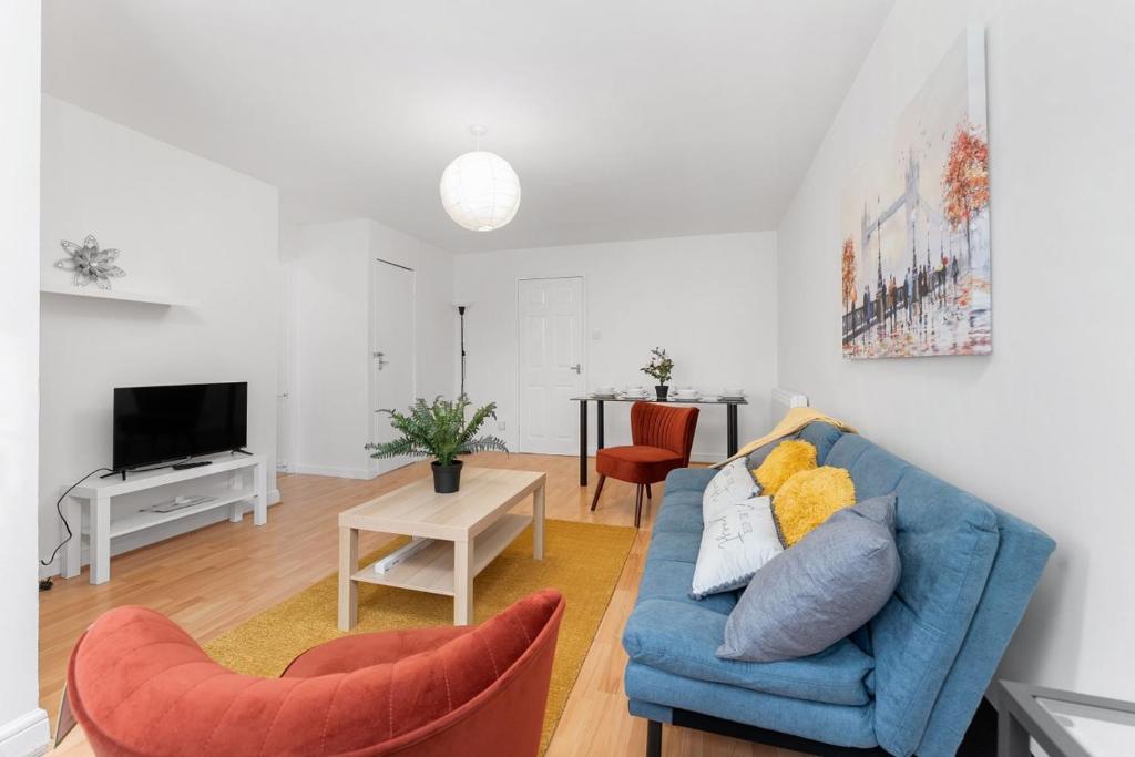 a living room with a blue couch and a table at The Mullard in Hackbridge