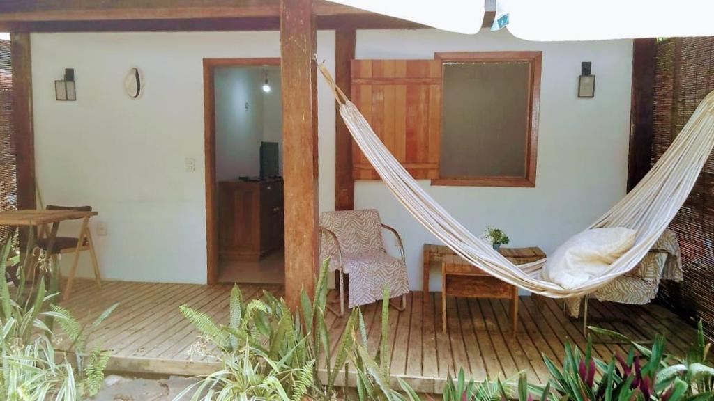 um alpendre com uma rede de descanso, uma mesa e cadeiras em Suites na Vila em Maraú
