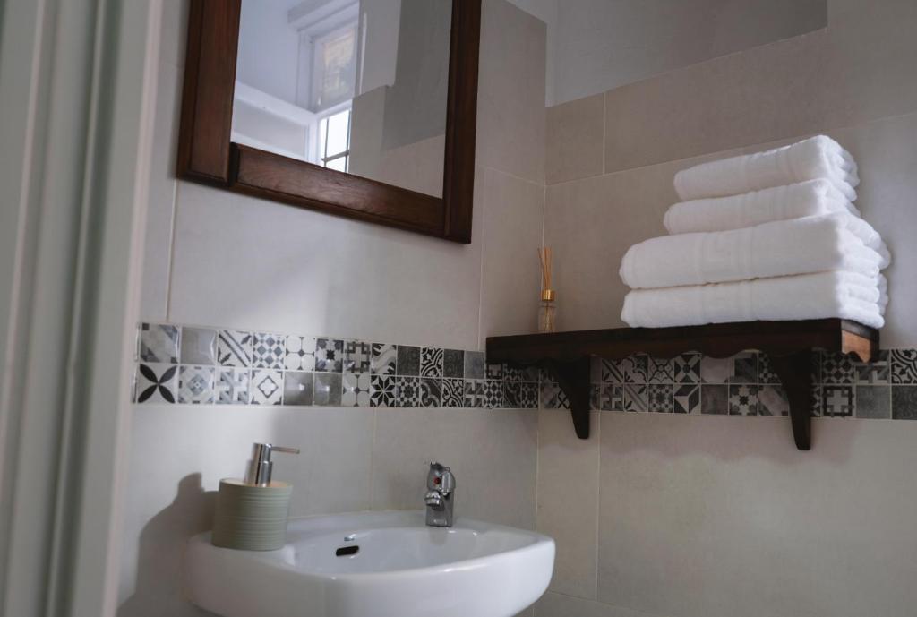y baño con lavabo, espejo y toallas. en Apartamento La Inmaculada en Ayamonte