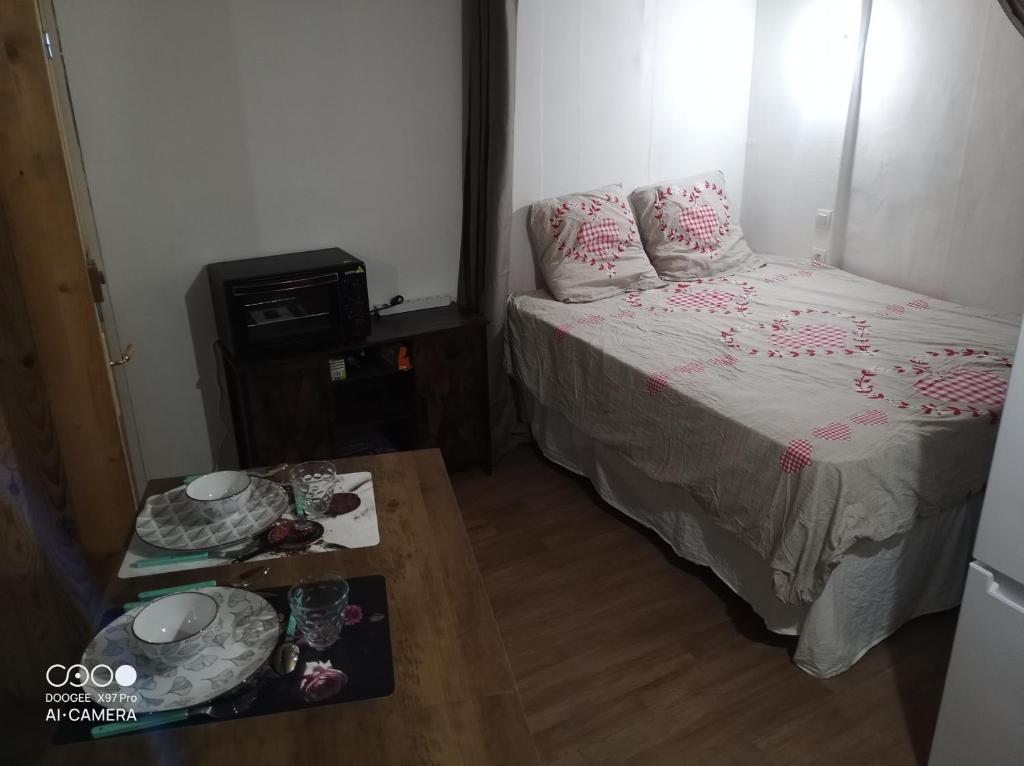 Habitación pequeña con cama y mesa con vajilla en Village où il fait bon de vivre, en Mauléon-Barousse