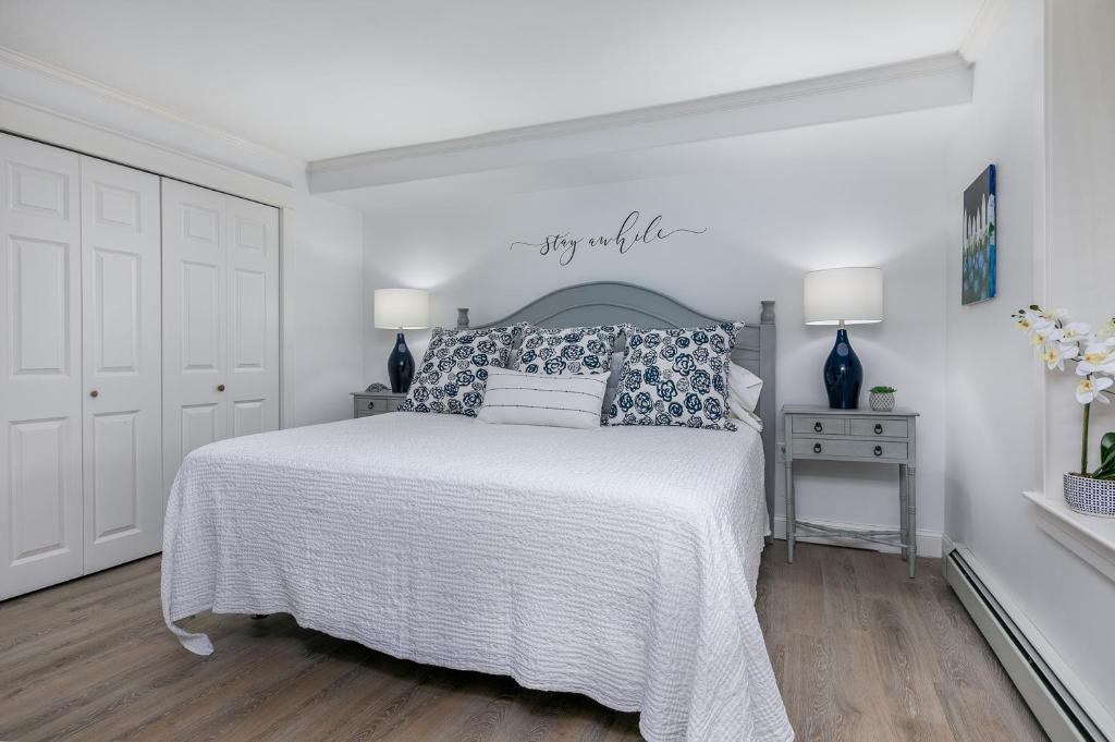 a white bedroom with a bed with a white bedspread at Beautiful PRIVATE Oasis - On the River's Edge in Kennebunk