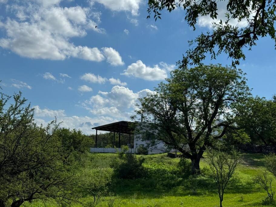 een gebouw in het midden van een veld met een boom bij La Lomita, Calamuchita, un plan de tranquilidad y naturaleza plena in Cordoba
