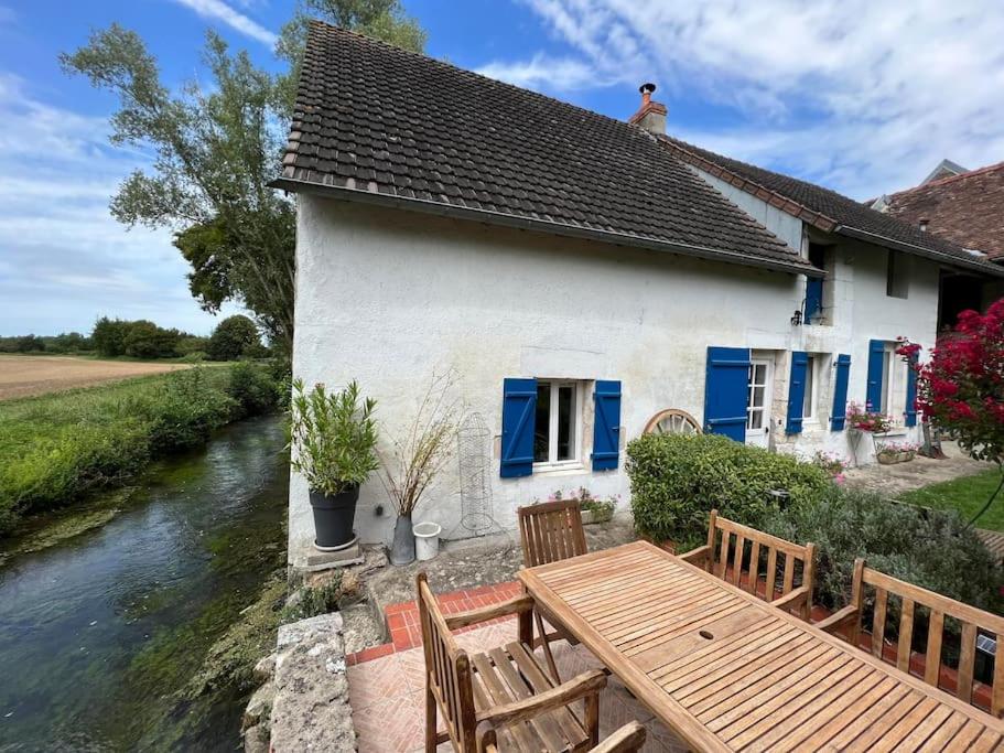 a house with a table and benches next to a river at Jolie maison de campagne au bord d'un ruisseau in Vinon