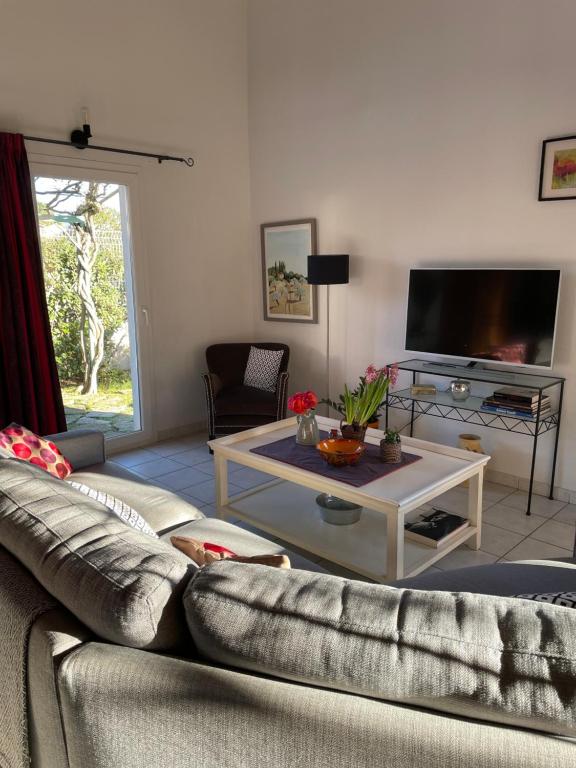 ein Wohnzimmer mit Sofa und Fernseher in der Unterkunft Charmante villa au calme proche de Montpellier, mer et rivière Animaux acceptés in Saint-Gély-du-Fesc